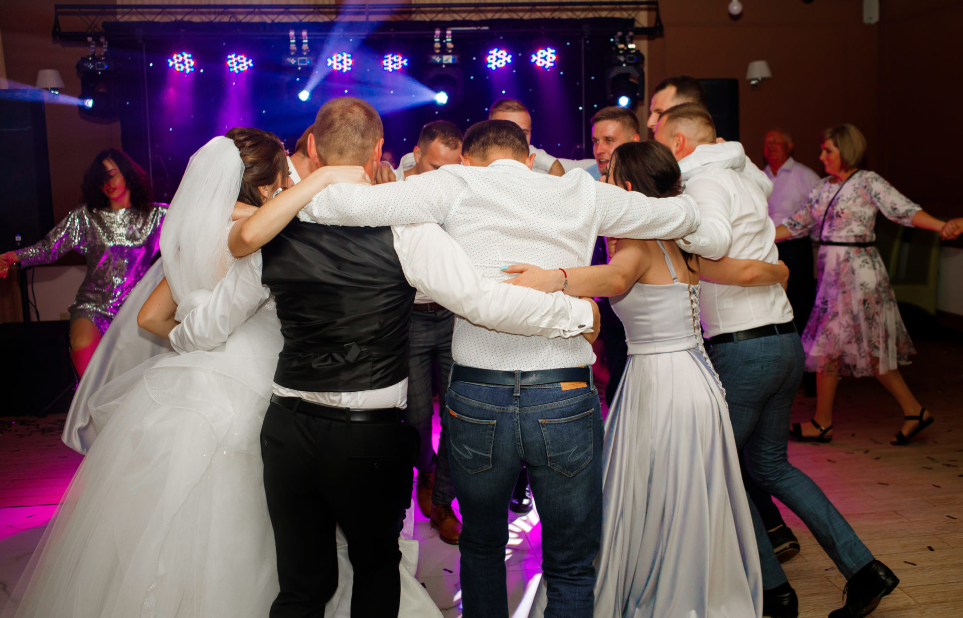 A group of guests dancing holding each other's shoulders.
